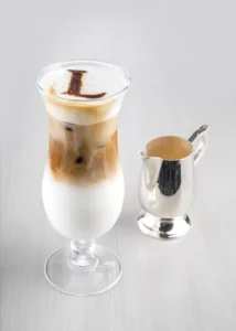 A Spanish latte, shown both hot in a cup and cold in a glass with ice and layered milk.