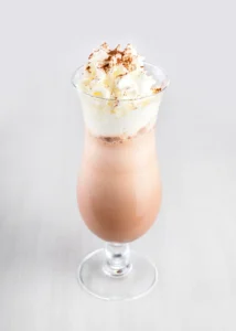 A tall glass of iced chocolate, with layers of milk and chocolate, topped with whipped cream.