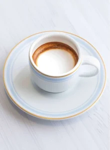 A small cup of espresso topped with a delicate dollop of milk foam.
